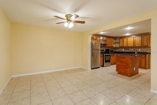 kitchen featuring light tile patterned floors, appliances with stainless steel finishes, decorative backsplash, a center island, and sink