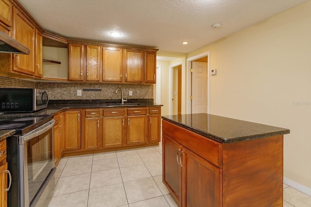 kitchen featuring appliances with stainless steel finishes, a kitchen island, dark stone counters, sink, and light tile patterned floors