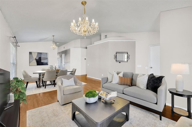 living room featuring an inviting chandelier, lofted ceiling, and light hardwood / wood-style floors