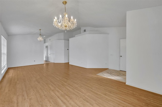 unfurnished living room with a notable chandelier and light wood-type flooring