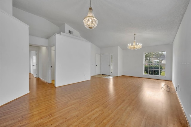 unfurnished living room with vaulted ceiling, an inviting chandelier, a textured ceiling, and light hardwood / wood-style flooring