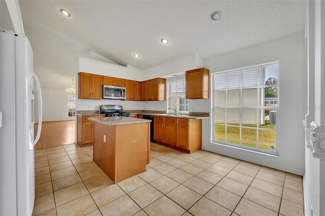 kitchen with a center island, lofted ceiling, white fridge, light tile patterned floors, and stove