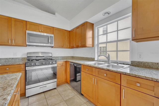 kitchen with vaulted ceiling, sink, light stone countertops, appliances with stainless steel finishes, and light tile patterned floors