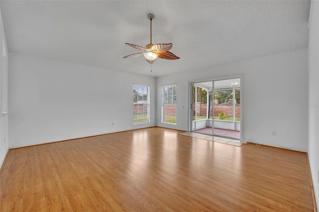 spare room with light wood-type flooring, ceiling fan, and a textured ceiling