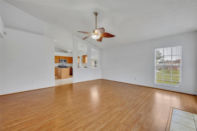 unfurnished living room featuring light wood-type flooring, ceiling fan, lofted ceiling, and a textured ceiling