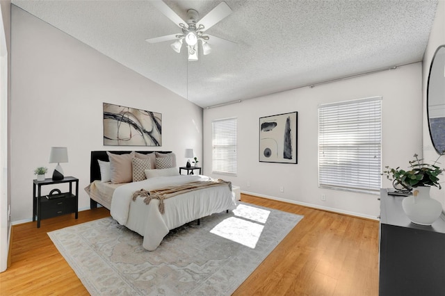 bedroom featuring a textured ceiling, ceiling fan, wood-type flooring, and multiple windows