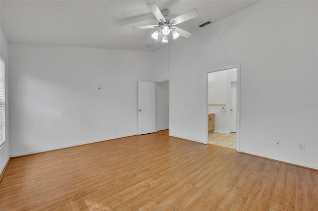 empty room with light wood-type flooring, ceiling fan, and a textured ceiling