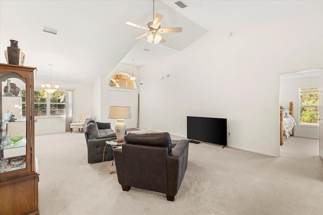 carpeted living room with ceiling fan with notable chandelier and high vaulted ceiling