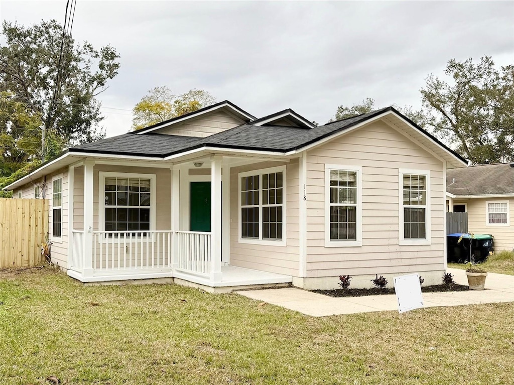 back of property featuring covered porch and a lawn