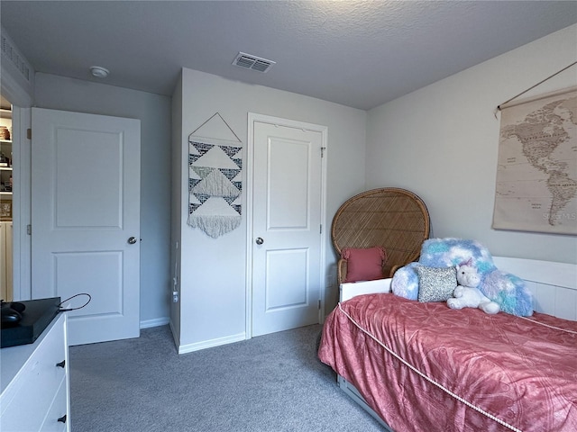 bedroom with a textured ceiling and dark colored carpet