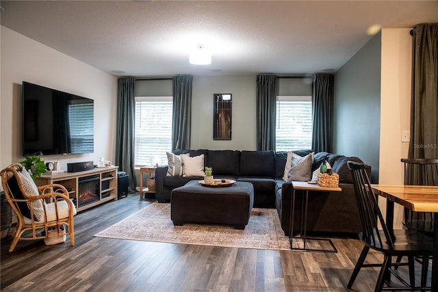 living room featuring a textured ceiling, dark hardwood / wood-style flooring, and a healthy amount of sunlight