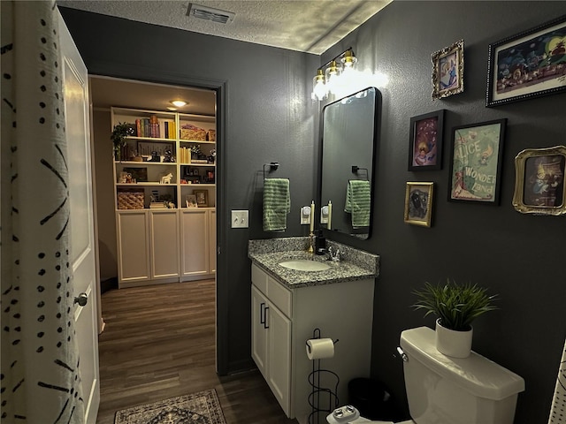 bathroom featuring toilet, vanity, a textured ceiling, and hardwood / wood-style flooring