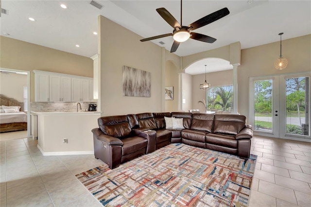 living room with decorative columns, french doors, light tile patterned floors, and ceiling fan