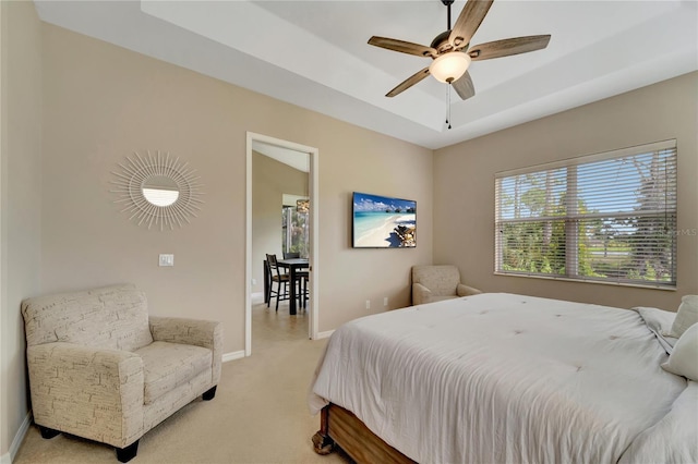 carpeted bedroom with ceiling fan and a raised ceiling