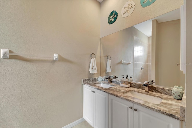 bathroom with tiled shower and vanity