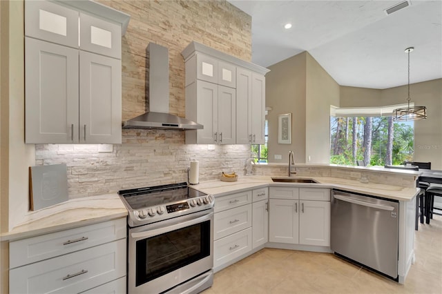 kitchen with white cabinets, appliances with stainless steel finishes, wall chimney exhaust hood, sink, and hanging light fixtures