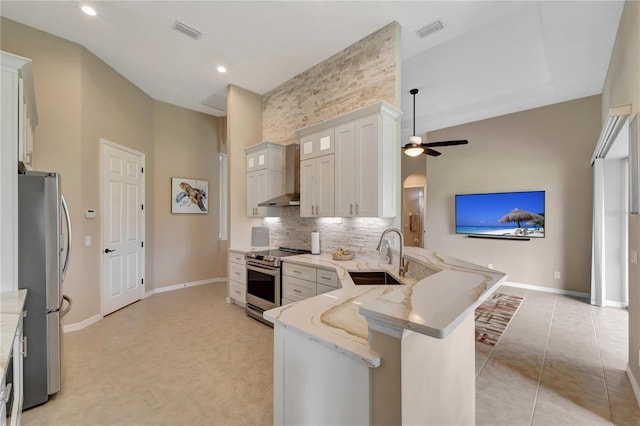 kitchen featuring kitchen peninsula, sink, white cabinetry, appliances with stainless steel finishes, and wall chimney exhaust hood