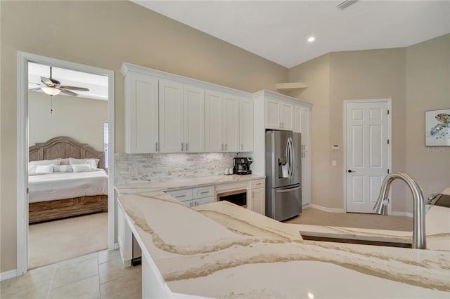 kitchen with stainless steel refrigerator with ice dispenser, light stone countertops, white cabinets, and ceiling fan