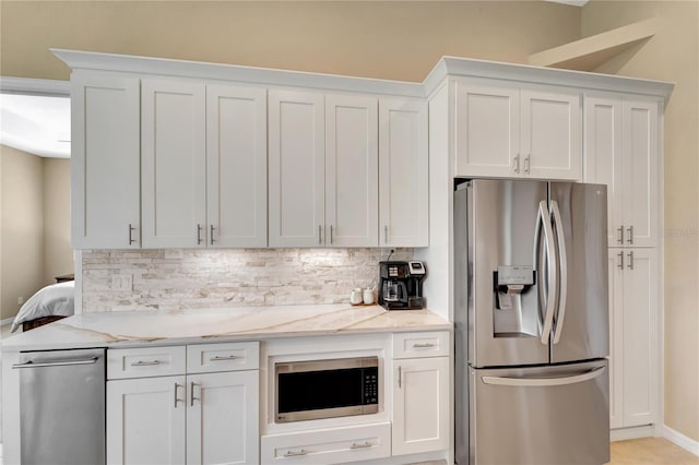 kitchen featuring appliances with stainless steel finishes, white cabinets, and tasteful backsplash