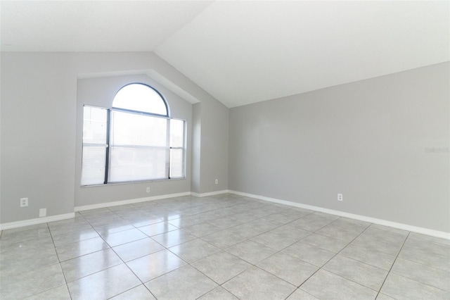 tiled empty room featuring a wealth of natural light and vaulted ceiling