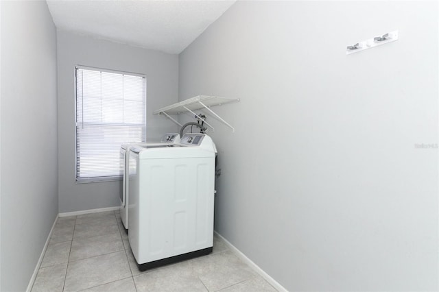 washroom with light tile patterned flooring, a textured ceiling, a wealth of natural light, and washing machine and clothes dryer