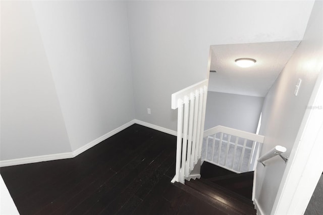 staircase featuring a textured ceiling and wood-type flooring