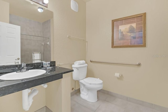 bathroom featuring tiled shower, toilet, tile patterned flooring, and sink