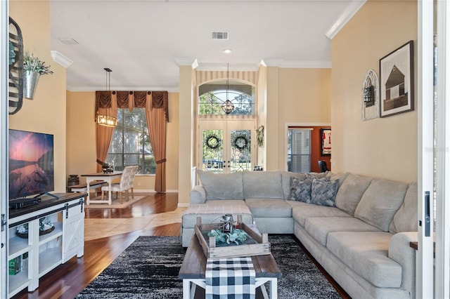 living room with french doors, ornamental molding, and a chandelier