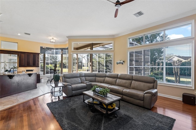 living room with sink, ornamental molding, light hardwood / wood-style floors, and ceiling fan