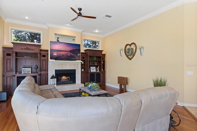 living room with hardwood / wood-style floors, a fireplace, ornamental molding, and ceiling fan