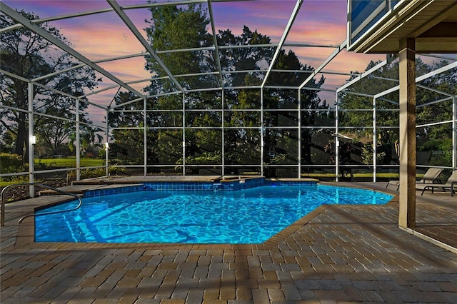 pool at dusk with a patio area and glass enclosure