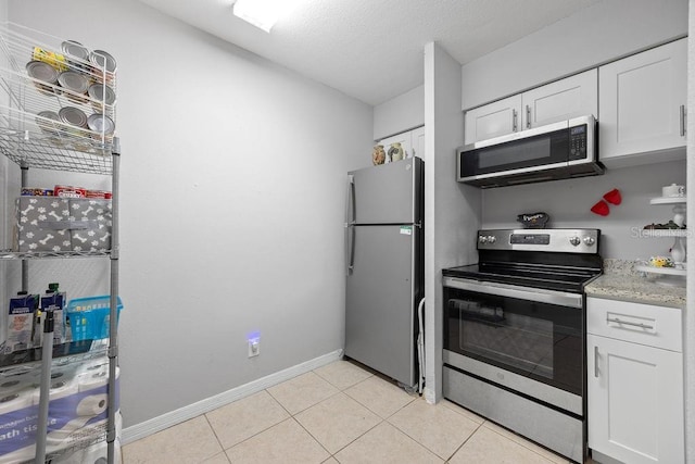 kitchen with light tile patterned floors, stainless steel appliances, and white cabinetry