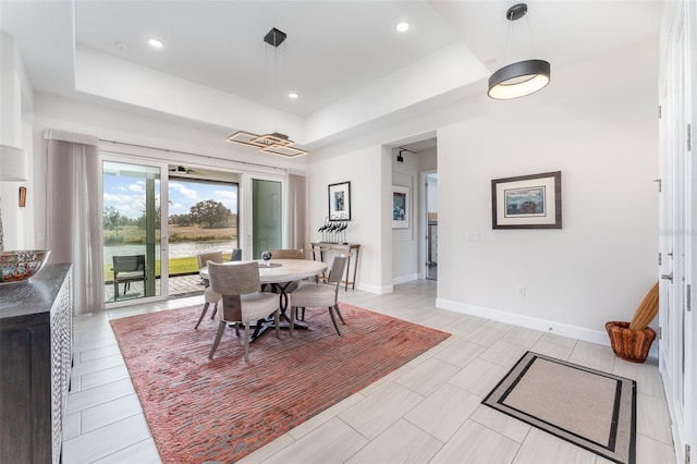 dining room featuring light tile patterned flooring and a tray ceiling