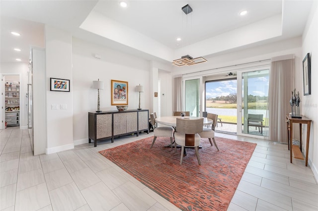 dining space featuring light tile patterned floors and a tray ceiling