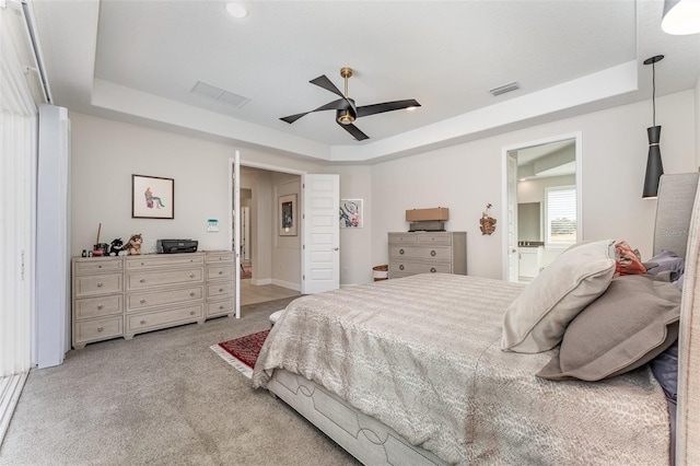 carpeted bedroom with connected bathroom, ceiling fan, and a raised ceiling