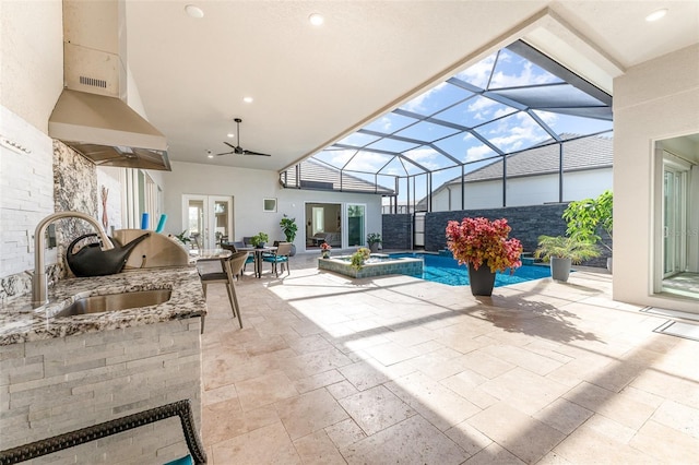 view of patio featuring sink, a lanai, an outdoor kitchen, and french doors