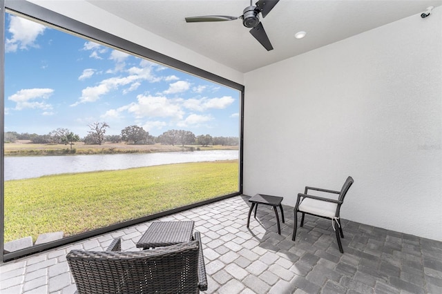 sunroom / solarium featuring ceiling fan and a water view