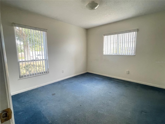 carpeted empty room with a textured ceiling