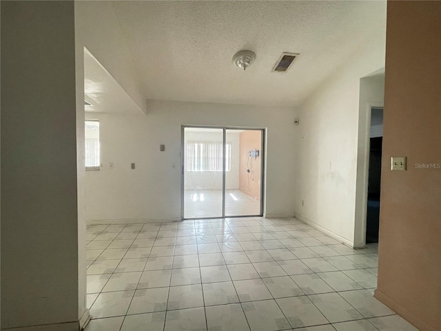 unfurnished room featuring light tile patterned flooring and a textured ceiling