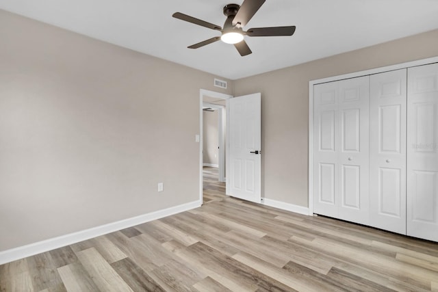 unfurnished bedroom with light wood-type flooring, ceiling fan, and a closet