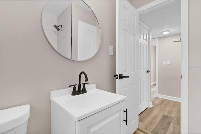 bathroom featuring toilet, a textured ceiling, wood-type flooring, and vanity