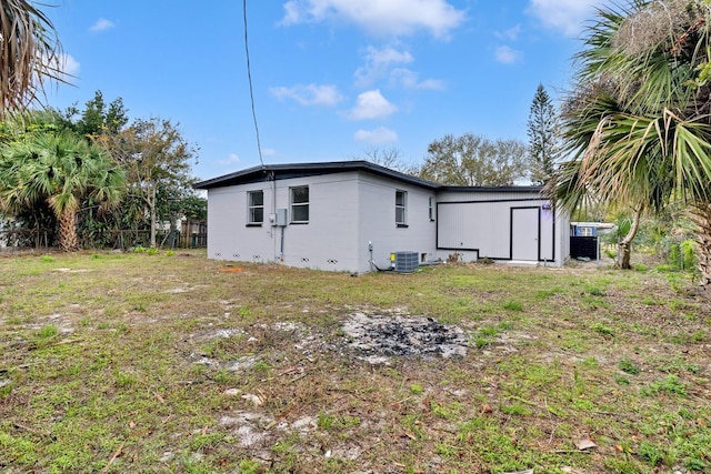 rear view of house featuring central air condition unit and a yard