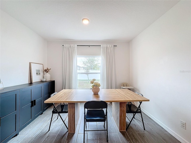 dining space with wood-type flooring and a textured ceiling