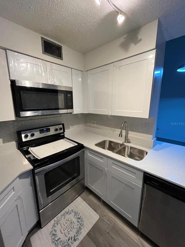 kitchen with white cabinetry, sink, stainless steel appliances, and a textured ceiling