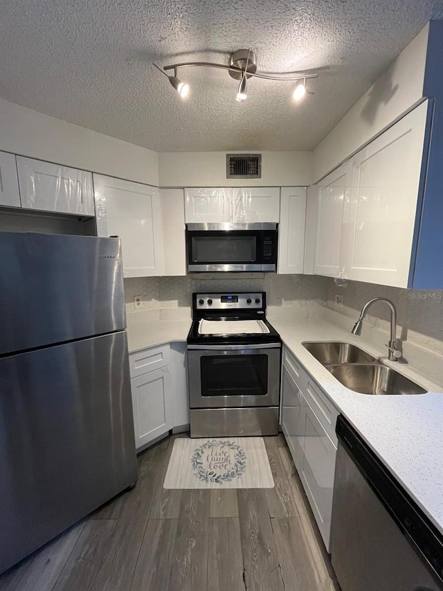 kitchen with sink, white cabinets, appliances with stainless steel finishes, and track lighting