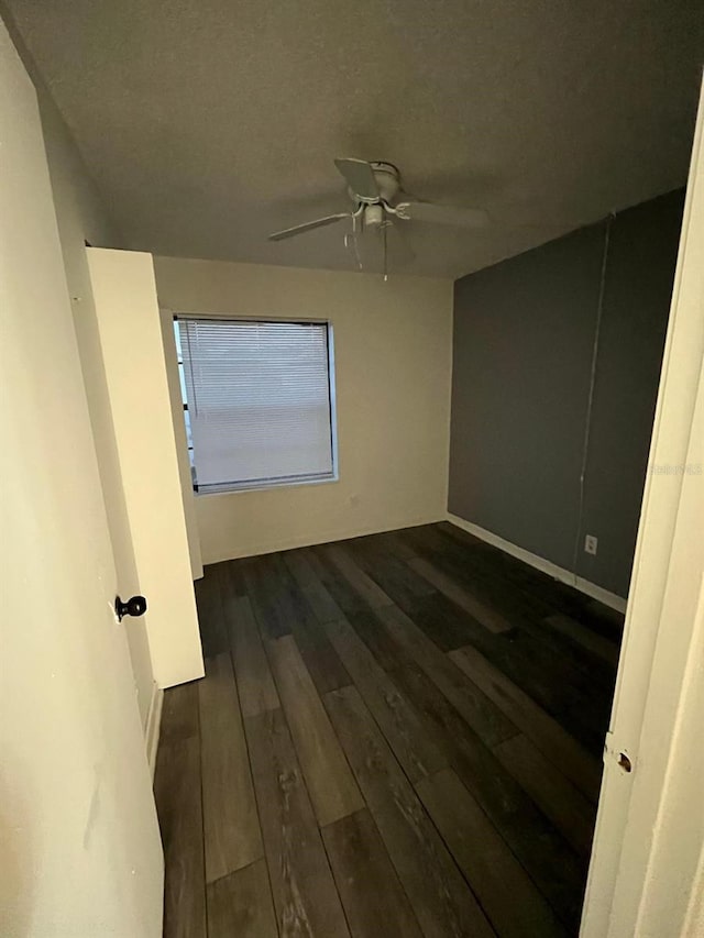 empty room with ceiling fan and dark wood-type flooring