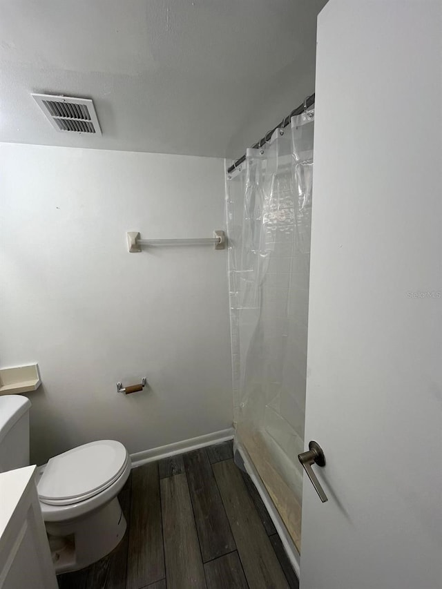 bathroom with toilet, vanity, wood-type flooring, and walk in shower