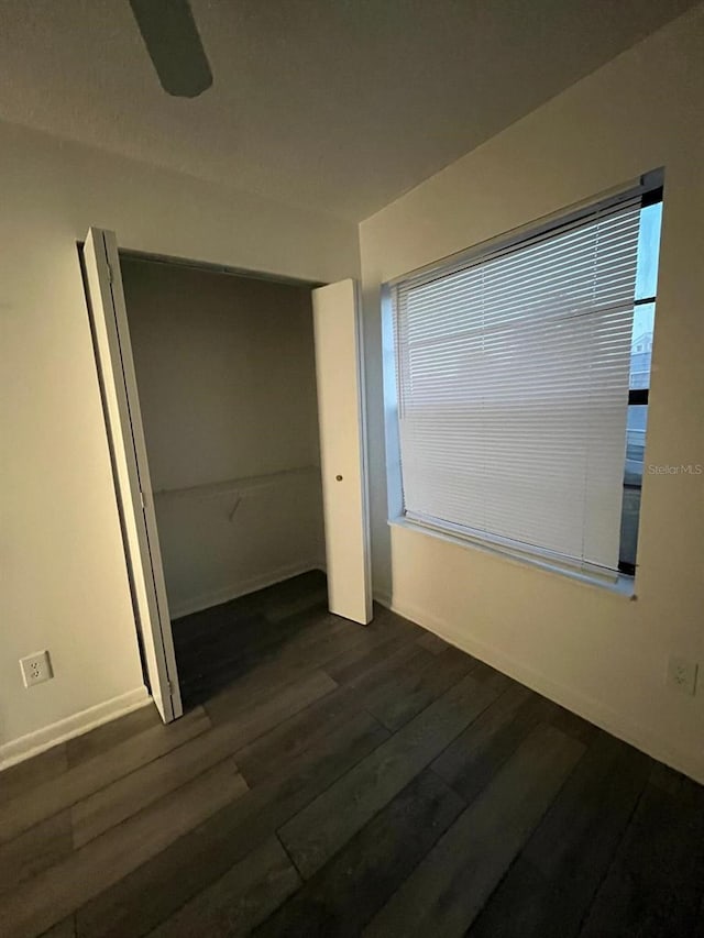 unfurnished bedroom with ceiling fan, a closet, and dark hardwood / wood-style flooring