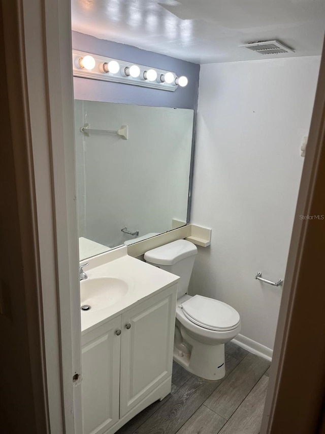 bathroom with toilet, vanity, and wood-type flooring