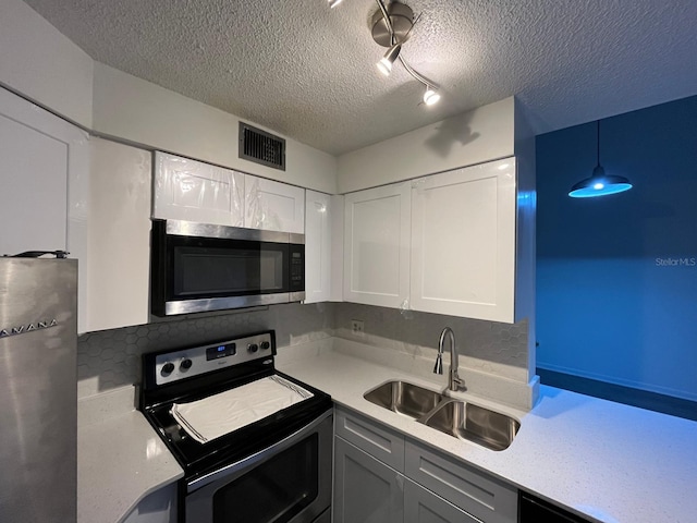 kitchen featuring sink, stainless steel appliances, hanging light fixtures, and white cabinets